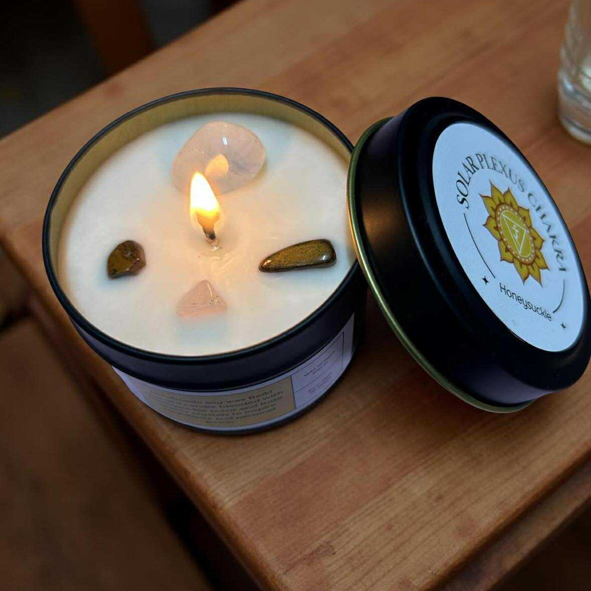 Candle in a jar with a lit wick on a wooden surface, brand label visible
