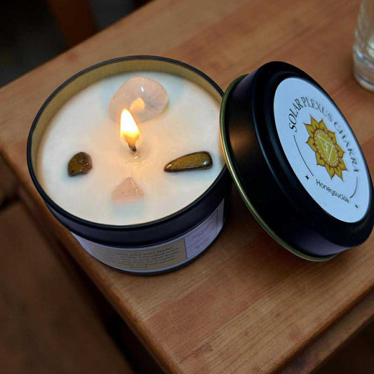 Candle in a jar with a lit wick on a wooden surface, brand label visible