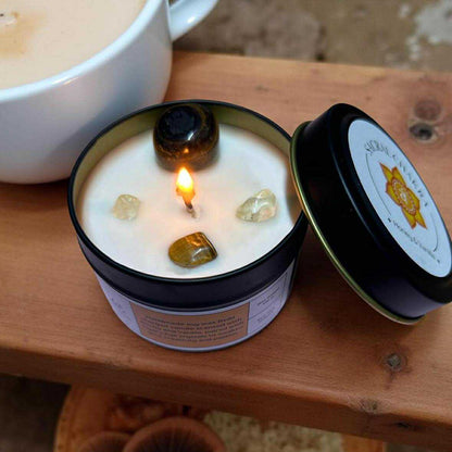 Candle in a tin with a lit wick on a wooden surface
