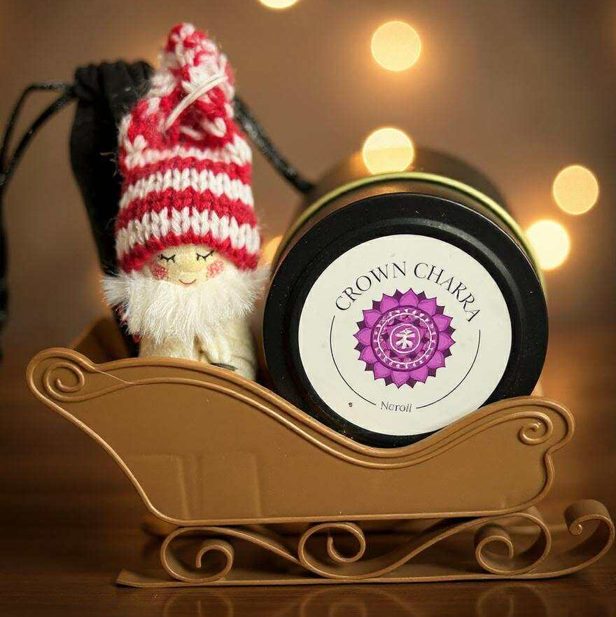 Candle in a decorative holder with a small gnome and blurred lights in the background