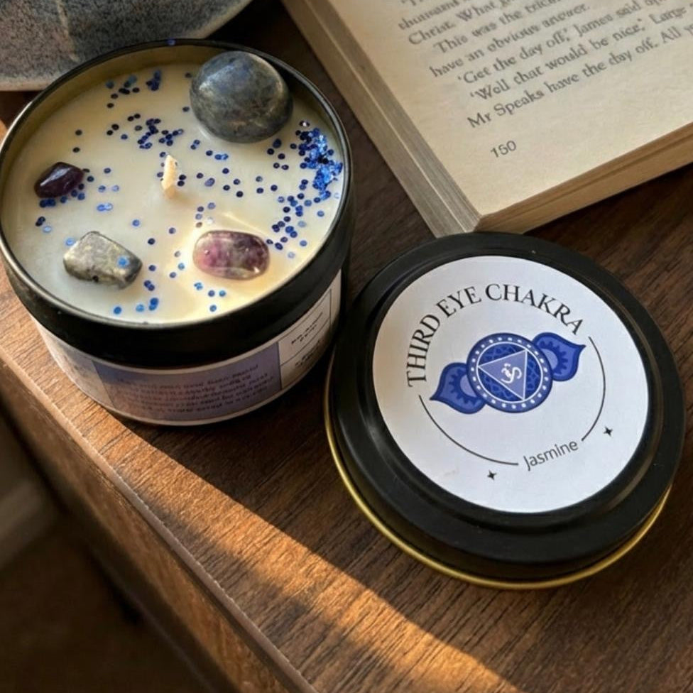 Candle with stones and a book on a wooden surface