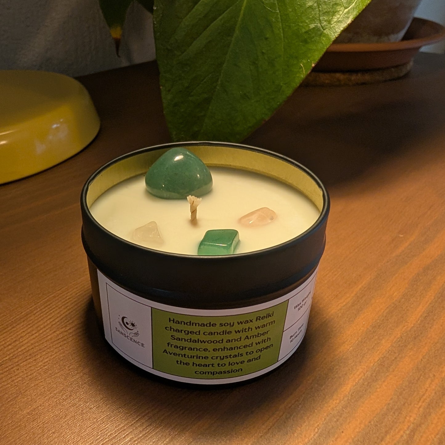 Candle in a tin with a green label on a wooden surface
