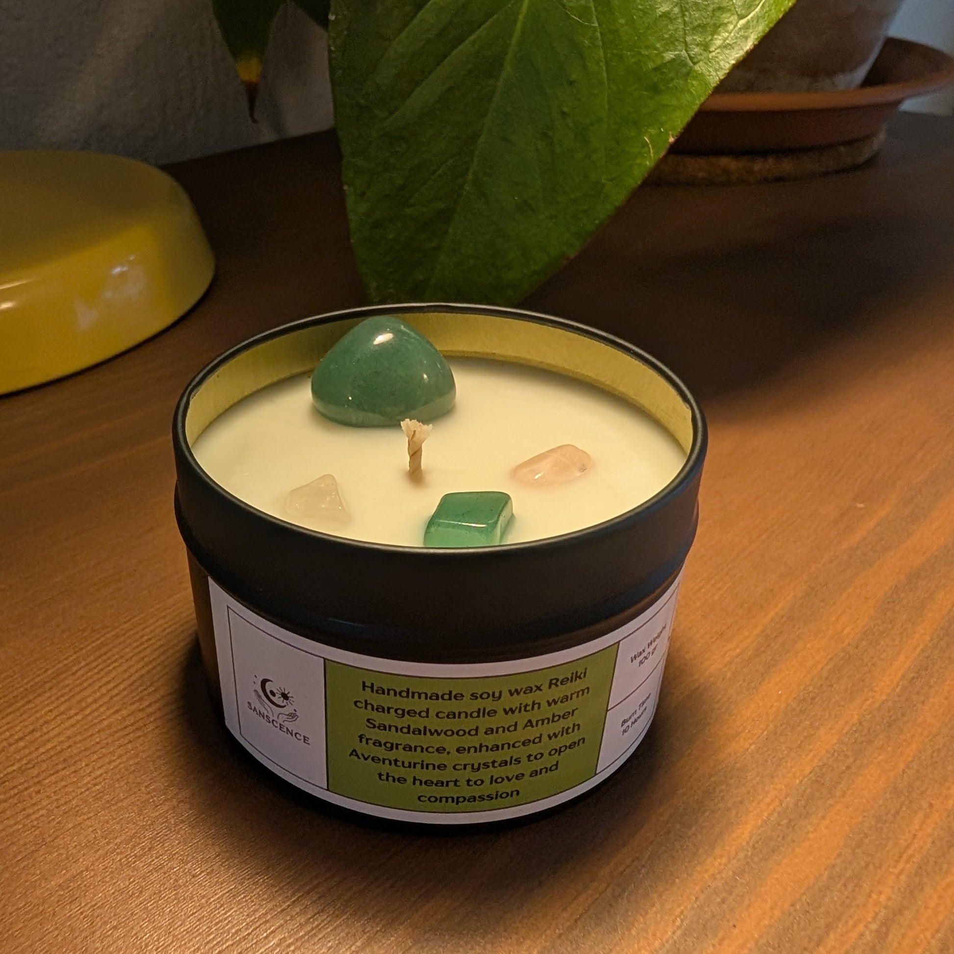 Candle in a tin with a green label on a wooden surface