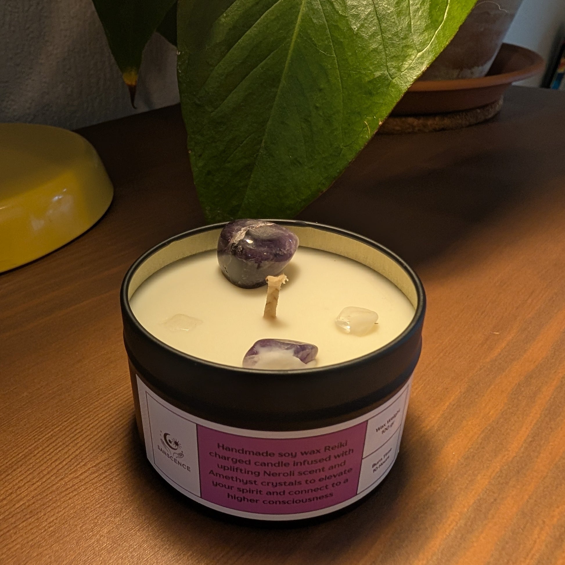 Candle in a tin with purple stones on a wooden surface