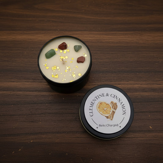 Candle with decorative stones and gold glitter in a black container on a light gray background