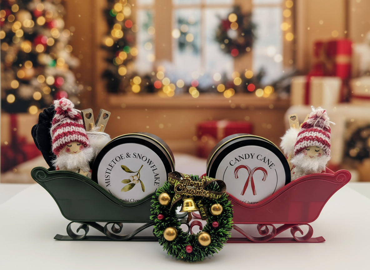 Two holiday-themed tins on a decorative sleigh with small figures and a wreath.