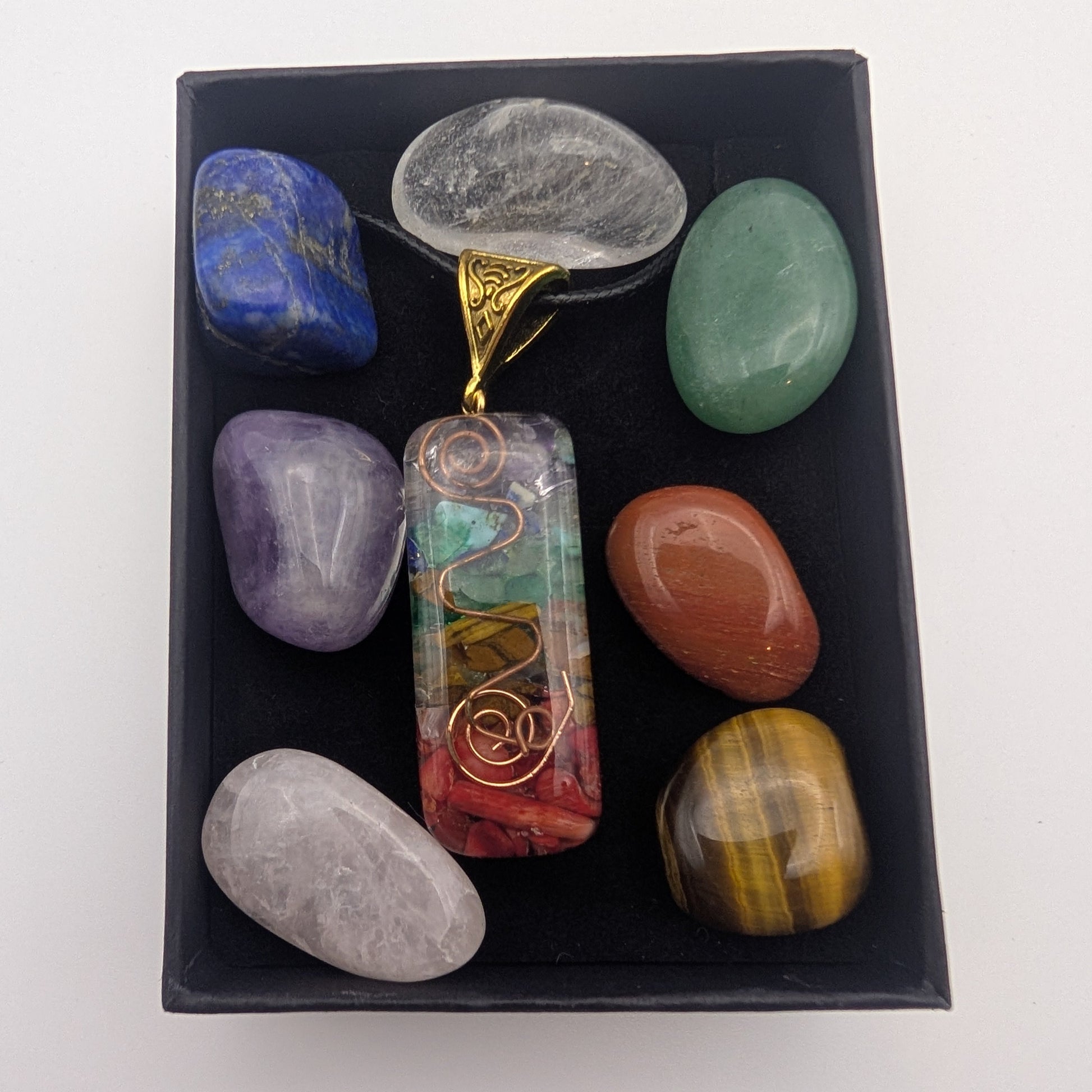 Set of colorful stones and a pendant in a black box on a white background
