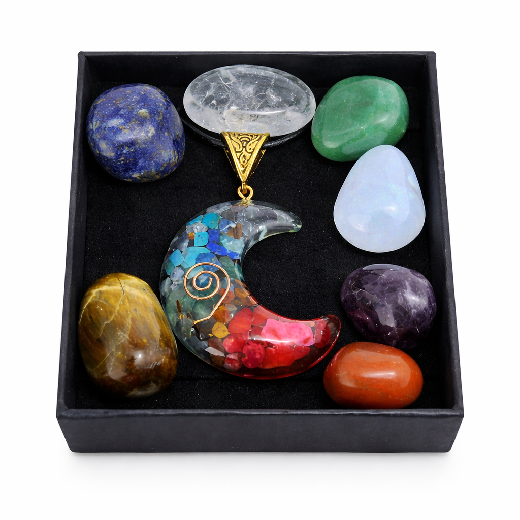 Set of colorful crystals and a moon-shaped pendant in a black box on a white background
