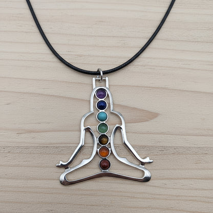 Silver pendant with colored stones on a black cord against a gray background