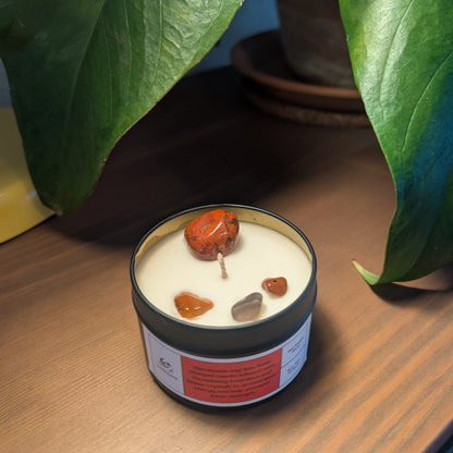 Candle with embedded stones on a wooden surface with plants in the background